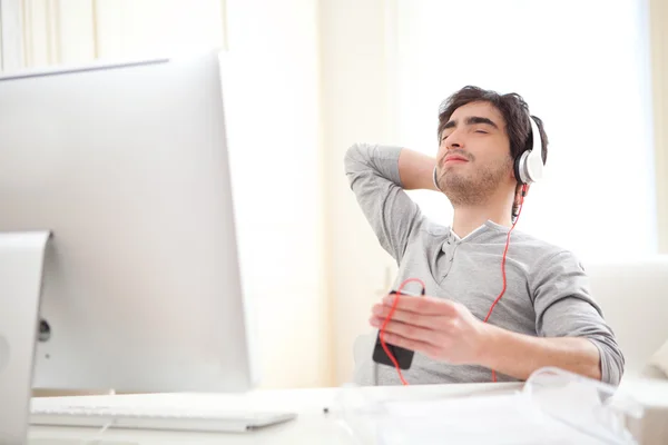 Young relaxed man listenning music at the office
