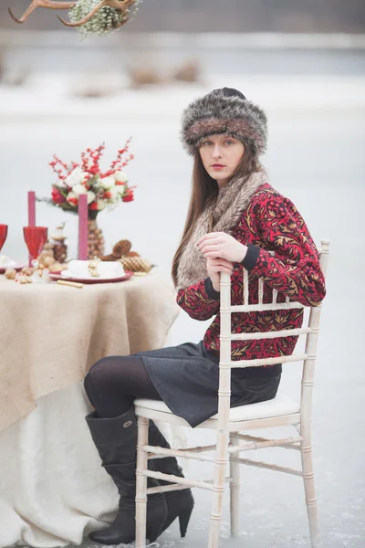 Beautiful girl in the park in winter, in a fur cap on a romantic