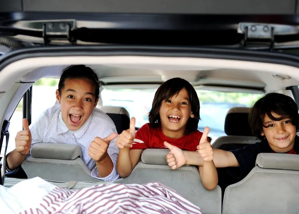 Smiling happy children in car with thumb up