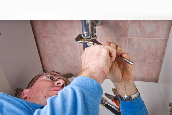 A plumber repairing a broken sink in bathroom