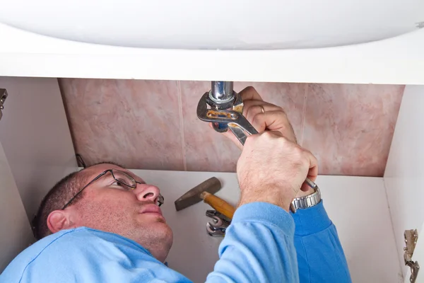 A plumber repairing a broken sink in bathroom