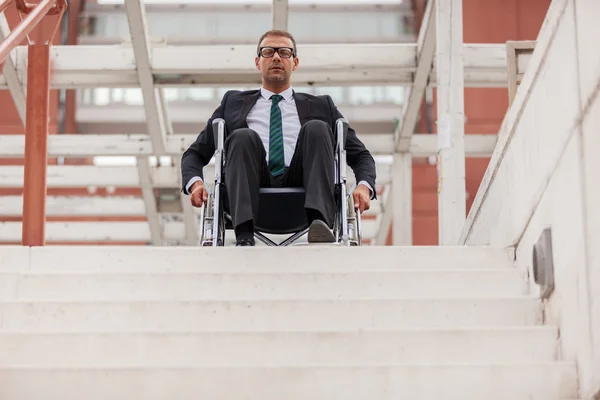 Businessman on wheelchair in front of stairs