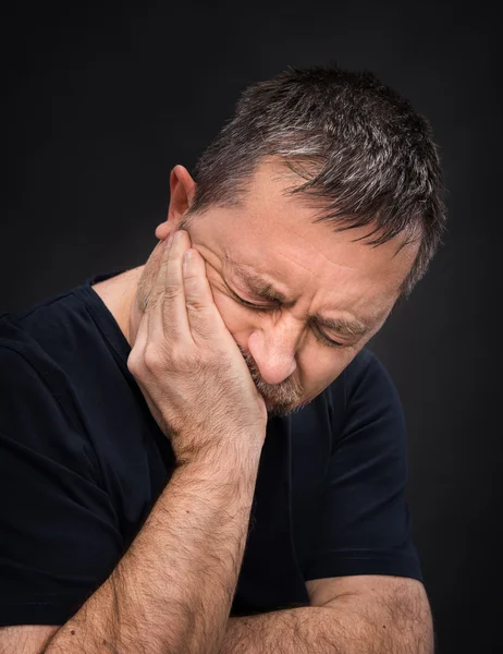 Toothache. Man with face closed by hand