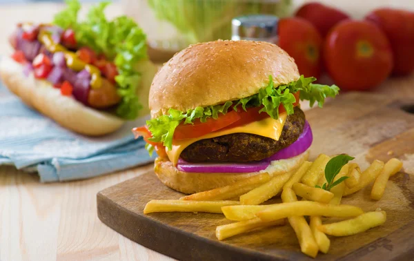 Burger and french fries with fast food ingredients on the backgr