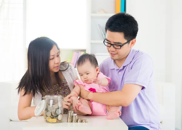 Asian baby putting coins into the glass bottle with help of pare