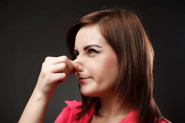 Young lady holding her nose because of a bad smell