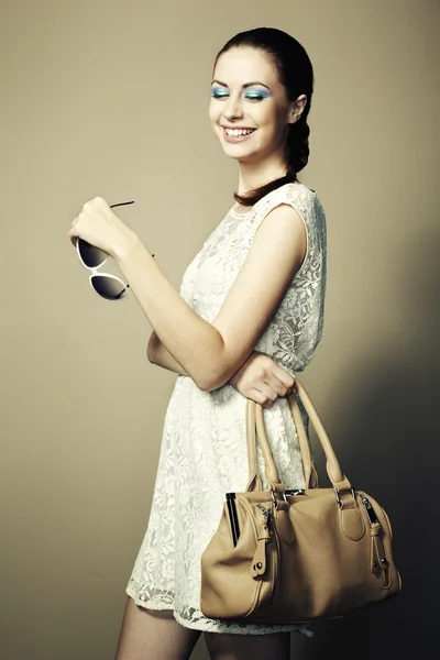 Portrait of young smiling woman with a leather bag