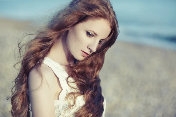 Beautiful woman with red hair at the sea