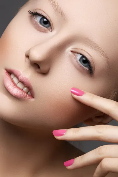 Beautiful young model with natural make-up and bright pink manicure. Wellness. Close-up beauty portrait of lovely european woman with clean healthy skin, pale lips, vibrance nail polish. Spa look