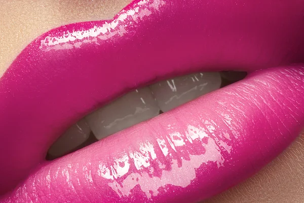 Close-up of woman's lips with bright fashion pink glossy makeup. Macro magenta lipgloss make-up