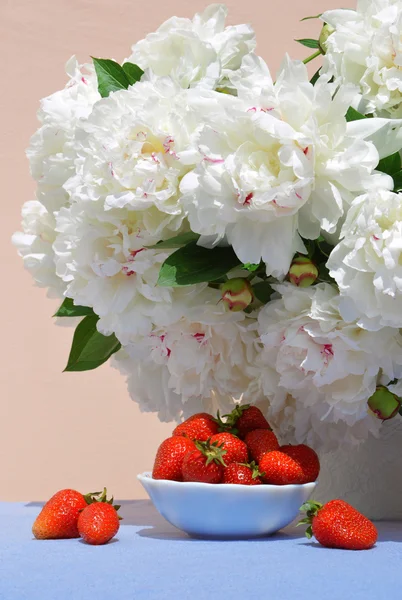 Strawberries in saucer on background of white peonies