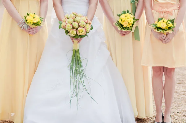 Three wedding bouquets being held by a bride and her bridesmaids