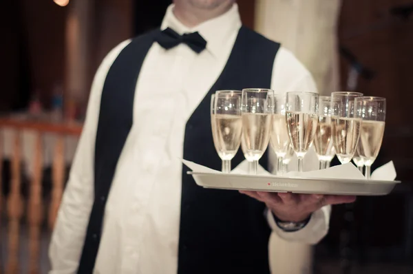 Professional waiter in uniform is serving champagne