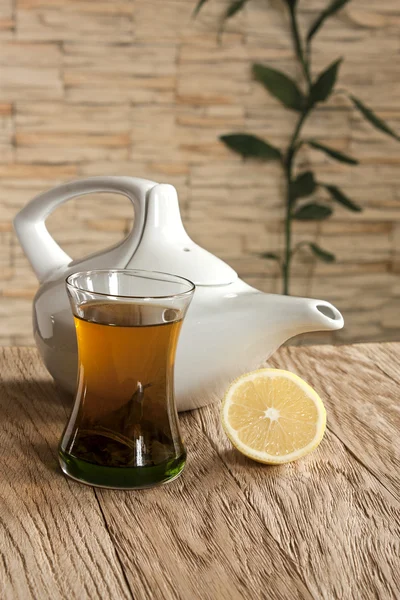 Cup of green tea and white tea kettle