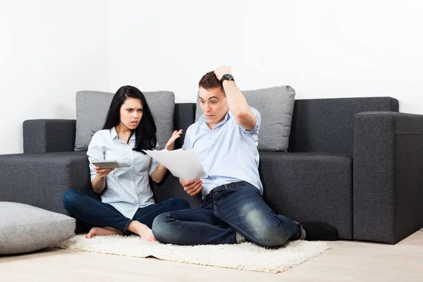 Unhappy couple reading a letter in the living room- money problem concept