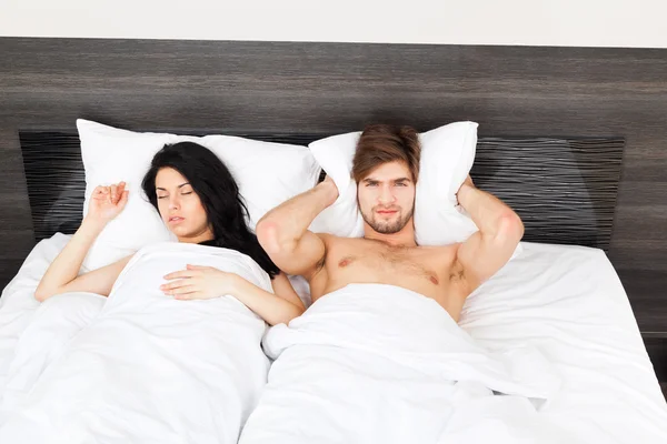 Couple in bed, snoring woman, man can not sleep