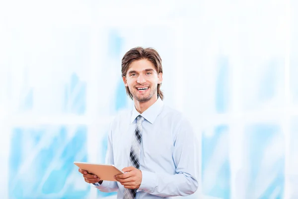 Business man using tablet pad computer in bright blue office, touch screen young businessman