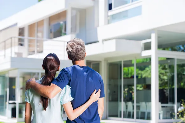 Couple embracing in front of modern house