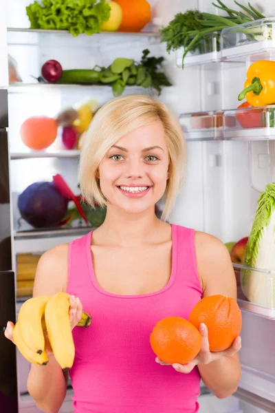 Woman holds banana and orange