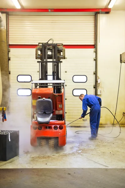 Worker cleaning forklift inside out
