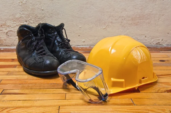 Yellow hard hat, old leather boots and protective goggles