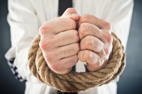 Businessman with hands tied in ropes