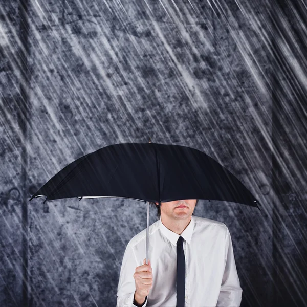 Businessman with black umbrella protecting from rain