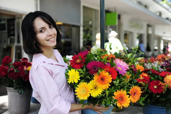 Woman with huge bouquet of flowers outdoors