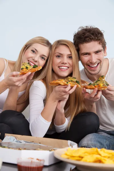 Group of young people eating pizza at home