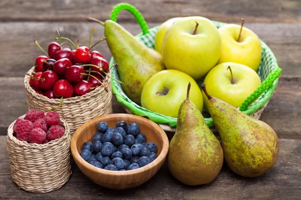 Fresh juicy apples, pears and berries on a wooden table