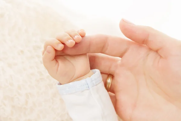 Newborn baby hand holding parent finger