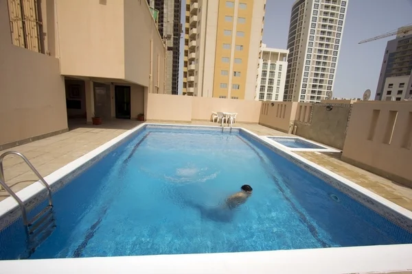 Man swim in swimming pool at roof of apartment, bahrain