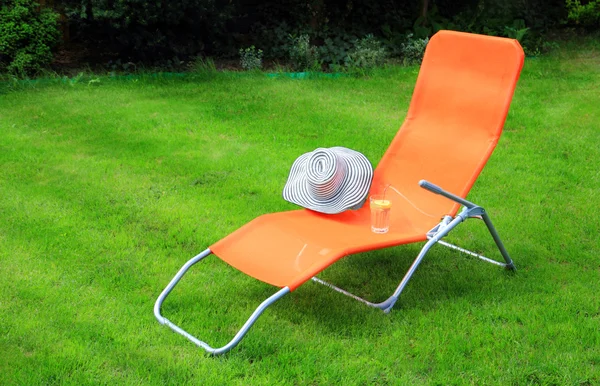 Orange lounge sunbed standing on green grass