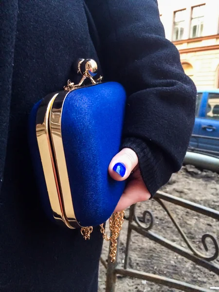 Woman holding a blue handbag in her hand