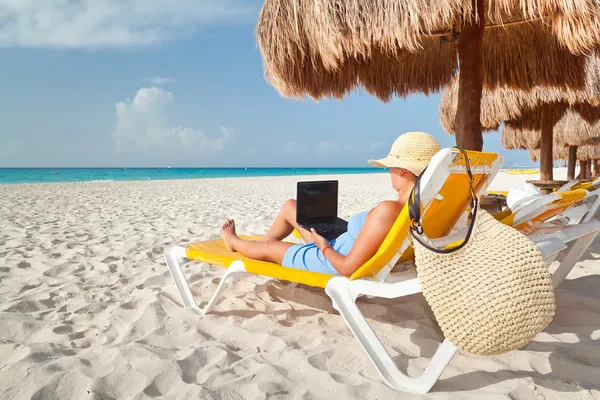 Woman with laptop relaxing on the deck chair
