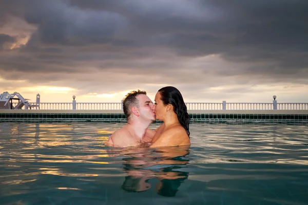 Kiss of loving couple in the swimming pool