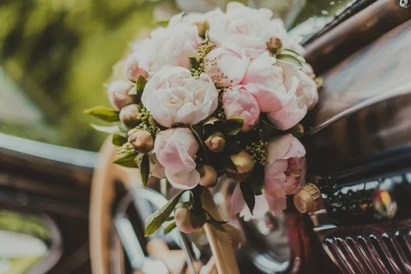 Bride\'s bouquet resting on a vintage wedding car