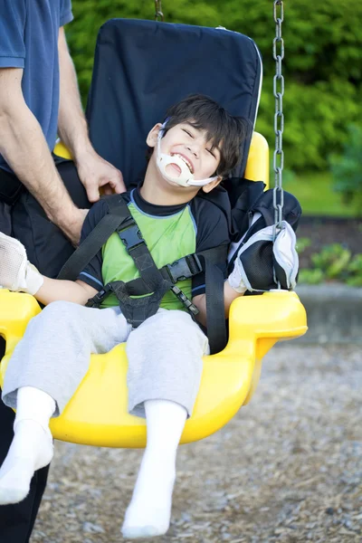 Disabled five year old boy in handicap swing