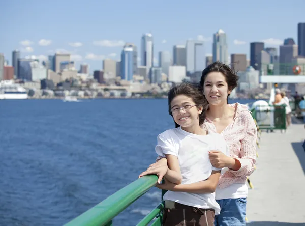 Two sisters on ferry deck with Seattle skyline in background