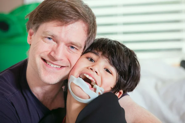 Smiling father holding disabled son