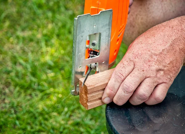 Builder working with electric jigsaw and wood