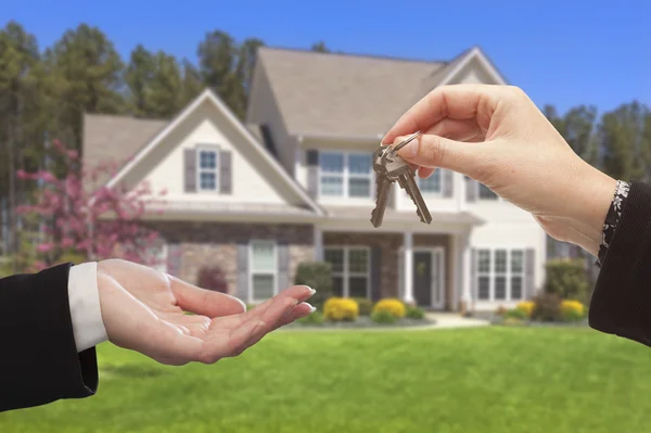 Agent Handing Over the House Keys in Front of New Home