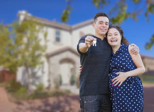 Hispanic Couple with House Keys In Front of New Home