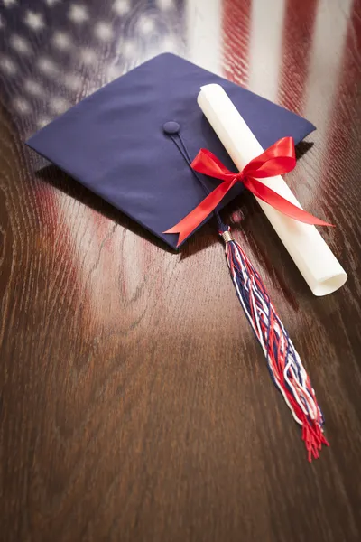 Graduation Cap and Dipoma on Table with American Flag Reflection