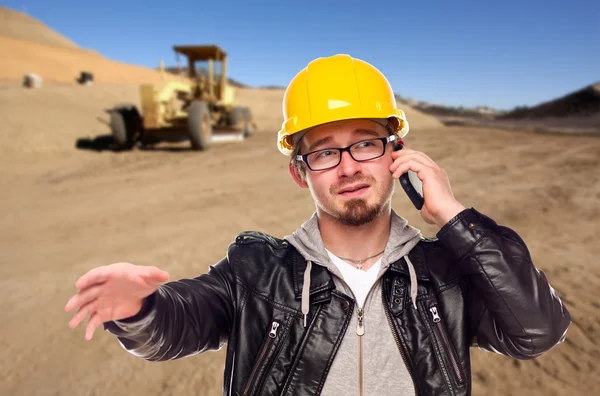 Young Cunstruction Worker on Cell Phone in Dirt Field with Tract