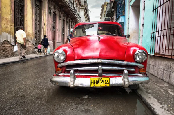 Old red car in a shabby street in Havana