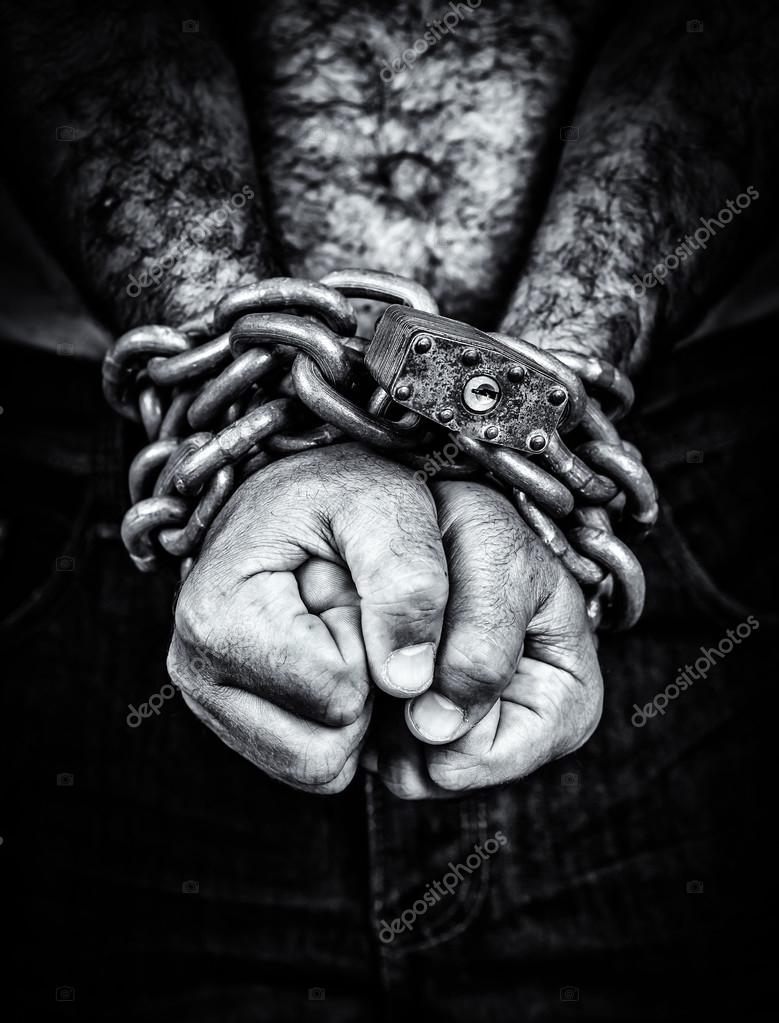 Two hands locked with a chain on a black background — Stock Photo