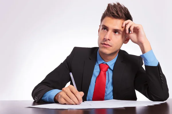 Man at desk thinking what to write