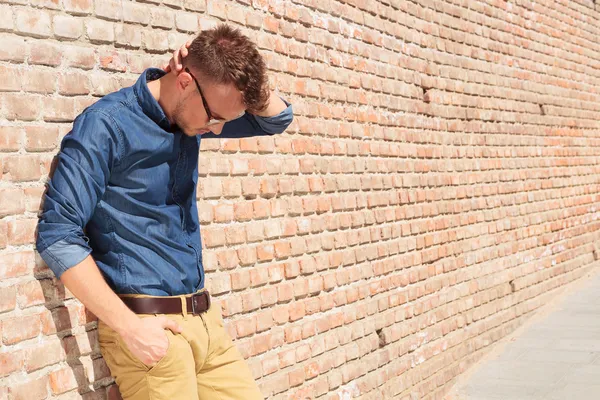Casual man standing upset by brick wall