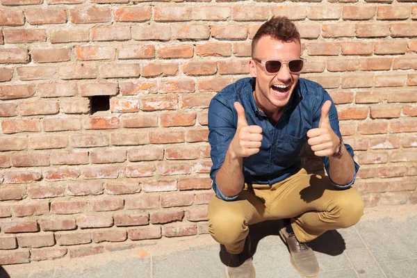 Casual man thumbs up by wall